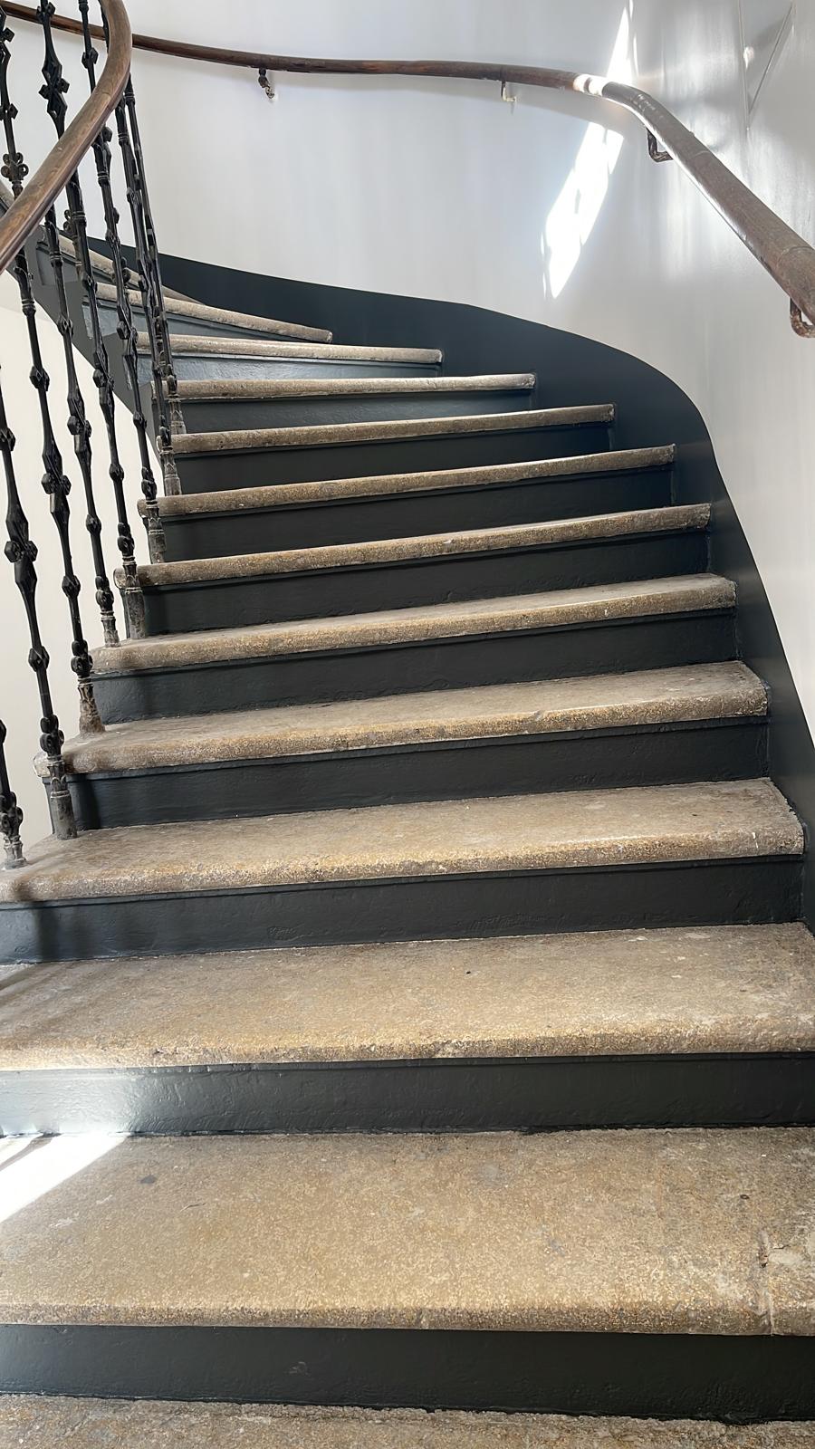 Fertiggestelltes Stiegenhaus mit dunklen Setzstufen und Wanddetail